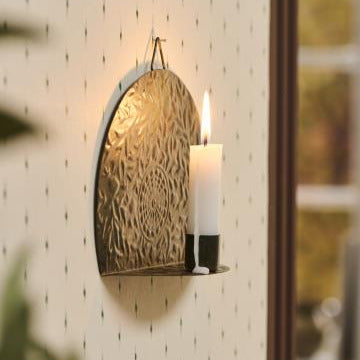 Decorative wall sconce with a candle on a white tiled wall.